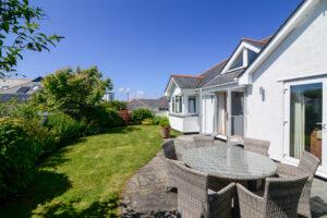 Rear exterior of Tregarne with outside dining furniture on the patio and grassed lawn