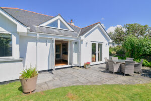 The rear grassed lawn and patio at Tregarne with double doors into the lounge