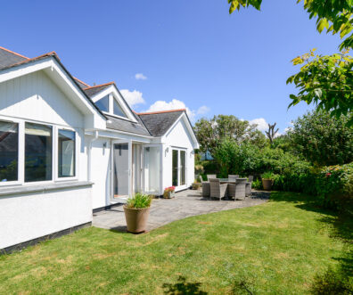 Rear exterior of Tregarne with outside dining furniture on the patio with double doors leading into the lounge