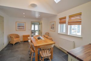 The dining table and chairs at Tregarne with door to entrance hall and windows to the front of the house