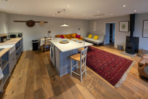 Open plan kitchen, dining island and lounge with log burner at The Studio at Pensile House
