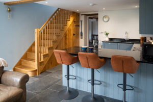 Open plan kitchen, bar stools and stairs to first floor at Carrek Cottage