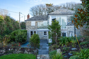 External view of back of Carrek Cottage, patio and shrubs in garden