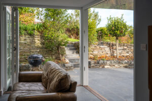 Sliding corner glass doors open onto patio and BBQ at Carrek Cottage