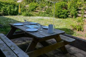 Outside garden and patio area to the rear of Stable Cottage with wooden picnic table