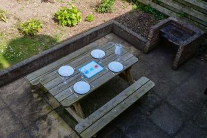 View of the rear patio area at Stable Cottage showing wooden picnic table and built in barbeque