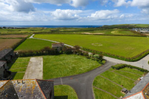Aerial view over the grassed area at the front of Stable Cottage over Trevose Golf Club towards Trevose Head