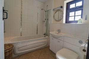 Bathroom on the ground floor at Stable Cottage showing bath with shower over, wash hand basin and toilet