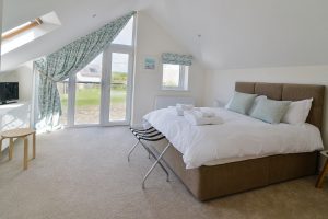 First floor ensuite king bedroom at Trebriani with large window and glass door and Juliet balcony
