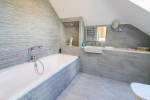 The ensuite to the first floor twin room with bath and handheld shower facility wash basin and toilet