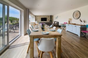 Open plan dining and lounge area at Trebriani with large doors onto the rear patio