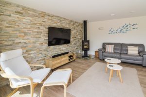 Open plan lounge area with seating and wood burner at Trebriani