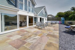 The rear paved and gravelled garden at Trebriani with large sliding doors into the open plan living area
