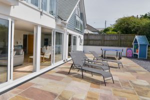 The rear paved and gravelled garden at Trebriani with large sliding doors into the open plan living area