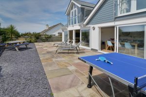 The rear paved and gravelled garden at Trebriani with loungers and picnic table and table tennis table