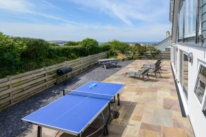 View over the rear paved and gravelled garden at Trebriani with outdoof furniture and table tennis table