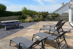 The rear paved and gravelled garden at Trebriani with loungers and picnic table
