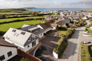 Aerial view over the front of Trebriani with neighbouring properties and ocean views toward Trevose Head