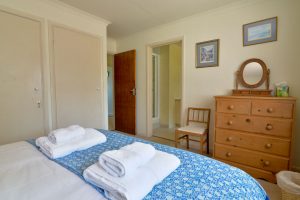 Ensuite king bedroom at Tamarisk with bedroom with chest of drawers and mirror