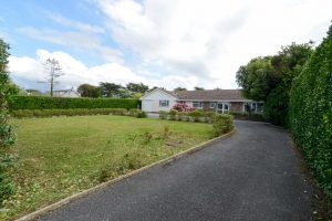 Front exterior of Tamarisk from driveway entrance showing grassed lawn and driveway to parking area