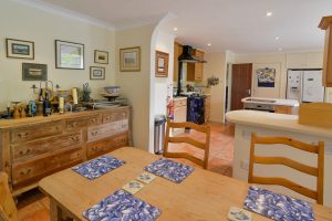 Dining and kitchen area at Tamarisk with dining table and chairs and large wooden sideboard