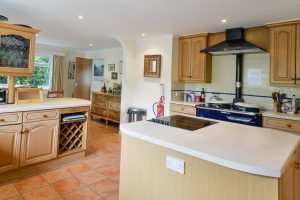 Kitchen area at Tamarisk with Aga and extractor over and kitchen island with electric hob