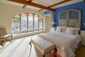 Master mezzanine bedroom at Church House with large stained glass window