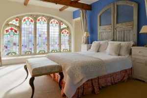Master mezzanine bedroom at Church House with large stained glass window