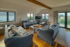 First floor lounge with ample seating and double doors onto balcony at Little Tremawr