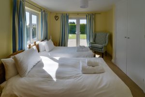 Ground floor twin bedroom with armchair at Little Tremawr and patio doors
