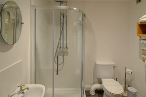 Ground floor bathroom with shower cubicle, toilet and wash basin at Little Tremawr