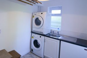 Utility room at Little Tremawr with sink, washing machine and dryer