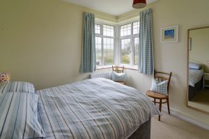 Double bedroom with corner window and wall hanging mirror