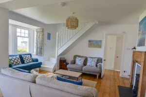 Lounge at Lowena with staircase, seating and log burner