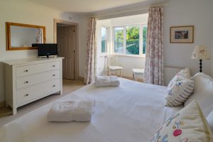 View of master bedroom with TV and door leading to ensuite at Bass Cottage.