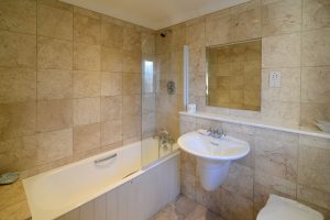 Main bathroom with overhead shower, bath, basin and loo at Bass Cottage