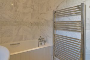 Bath and heated towel rail in ensuite at Bass Cottage