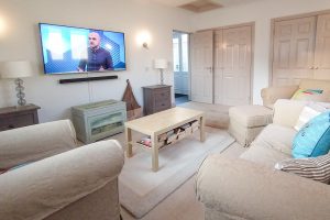 Cinema room at Bass Cottage with mounted TV and ample seating
