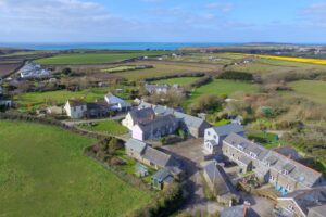 Aerial view of Treburrick Farm House onwards to the ocean and Trevose Head also showing other properties in the village