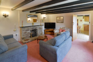 Lounge at Treburrick Farm House with beamed ceiling, fireplace, ample seating and television