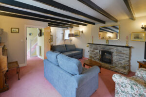 Lounge at Treburrick Farm House with beamed ceiling, fireplace, ample seating and television
