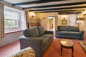 Lounge at Treburrick Farm House with beamed ceiling, ample seating doorway leading to 2nd set of stairs and dining room