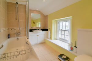 Bathroom with bath and shower over, wash hand basin and toilet at Treburrick Farm House