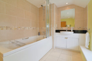 Bathroom showing bath with shower over and wash hand basin at Treburrick Farm House