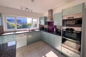 The kitchen area at Tristan with oven and integrated hob with extractor fan over and sink looking out to the rear garden