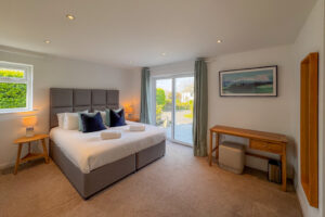The ensuite master bedroom at Tristan on the entrance floor level featuring a superking bed and double doors to a small paved area to the front of the house