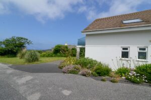 The side exterior of Tristan from the driveway showing the front lawn and parking area