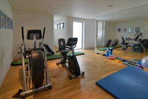 The Gym at Spin with exercise equipment and wall length mirrors. you need to go through the gym to get to the games and sofa room and the twin room