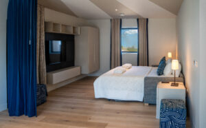 The made up sofa bed in the room off the games room on the ground floor at Spin with window to the side and wall mounted tv. The rooms can be separated by a floor to ceiling curtain