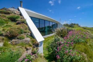 Exterior picture of the large window to the side of Spin with views out towards the ocean from the living room and the open plan kitchen and dining area